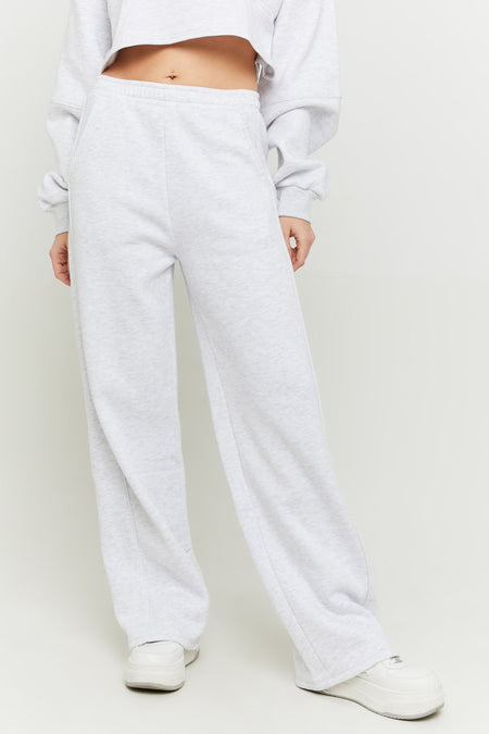 Grijze joggingbroek van TALLY WEIJL, met wijde pijpen en gedragen met een cropped sweater en witte sneakers.
