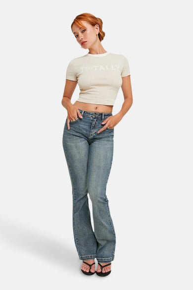 Middenblauwe bootcut jeans van TALLY WEIJL, gedragen met een cropped T-shirt en teenslippers.
