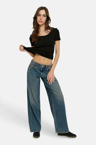 Lichtblauwe wijde spijkerbroek van TALLY WEIJL met verwassen effect, gedragen door een model met een zwarte crop top.