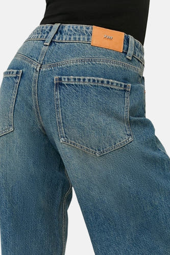 Lichtblauwe denim jeans met wijde pijpen van TALLY WEIJL, achterzijde met zakken, leren merkpatch en zwarte top.