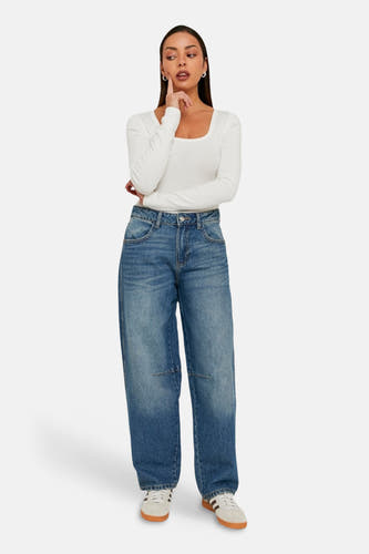 Jeans coupe spéciale en denim mi-foncé de TALLY WEIJL, avec jambes larges et chaussures blanches.