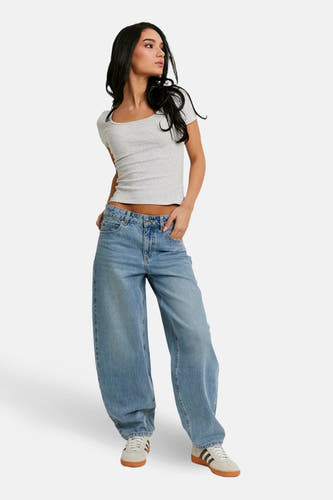 Jeans coupe spéciale en denim bleu clair de TALLY WEIJL, à jambes larges et porté avec un haut gris et des baskets basses.
