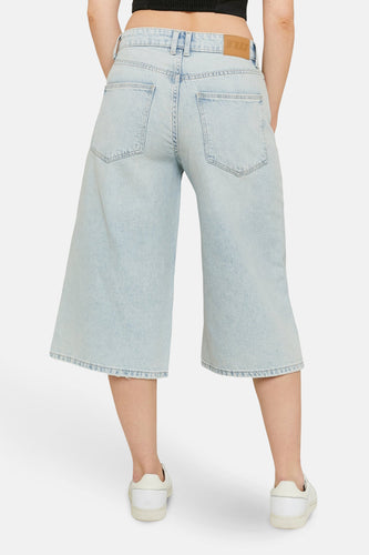 Lichtblauwe denim short van TALLY WEIJL, achterkant gezien, met witte sneakers en donkere top.
