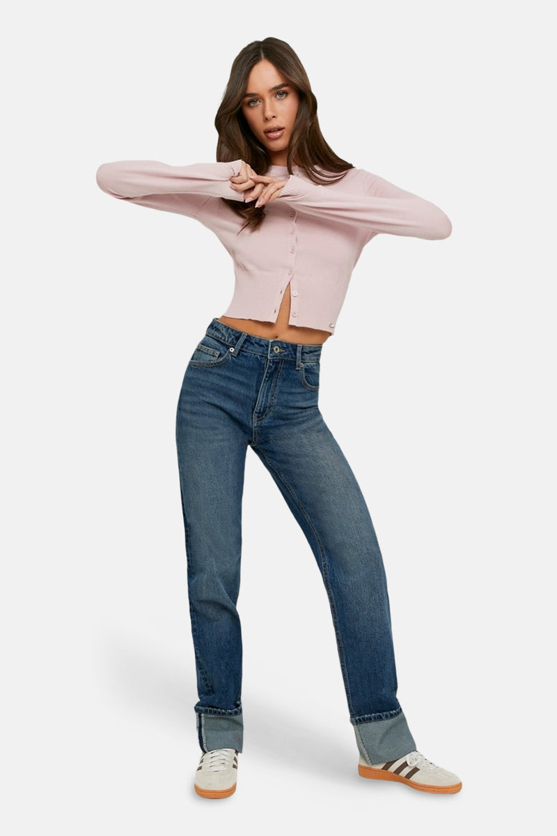 Jean large bleu de TALLY WEIJL, avec des jambes retroussées et porté avec un gilet rose et des baskets.