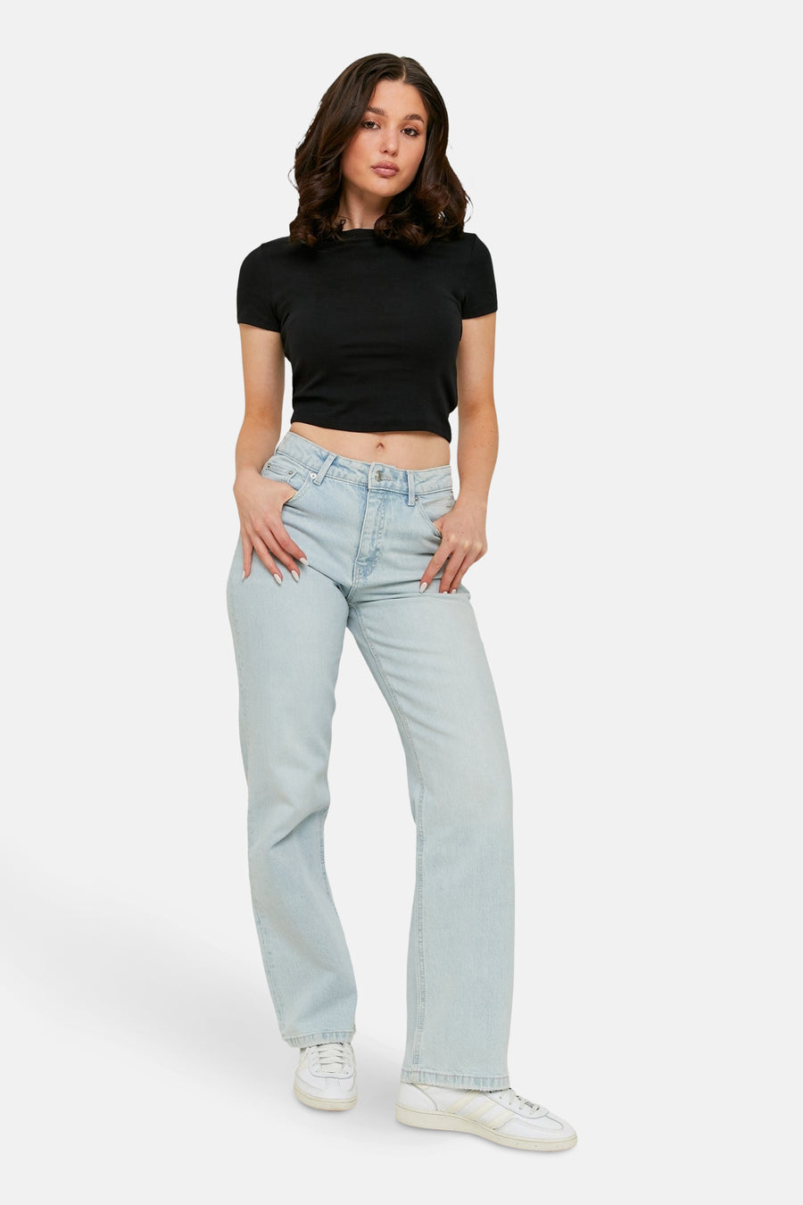 Jean droit bleu clair de TALLY WEIJL, porté avec un crop top noir et des baskets blanches.