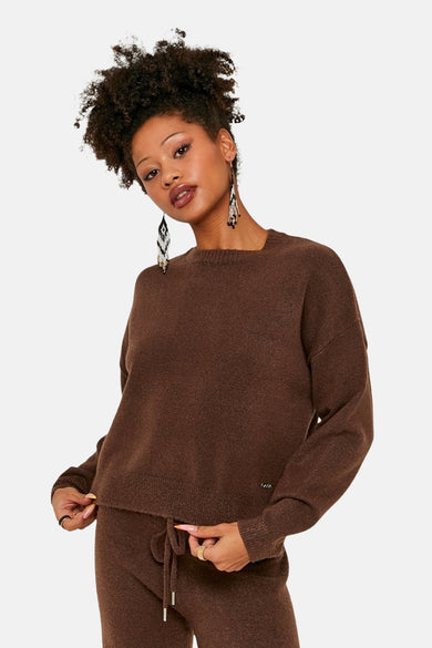 Sweat-shirt marron avec col rond de TALLY WEIJL, associé à un pantalon de la même couleur et des longues boucles d'oreilles.
