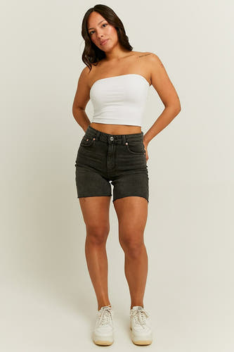 Zwarte denim short van TALLY WEIJL, met gerafelde zoom en gedragen met een witte top en witte sneakers.
