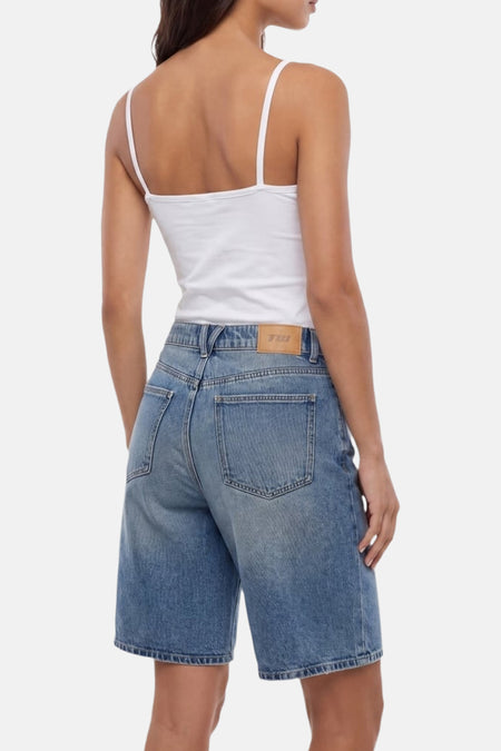 Short en jean bleu moyen de TALLY WEIJL, vue arrière, avec patch de marque marron clair et haut à fines bretelles blanc.