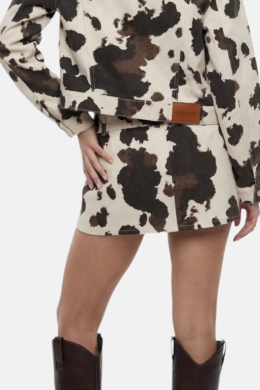 Jupe courte à imprimé vache beige et marron de TALLY WEIJL, portée avec une veste assortie et des bottes marron foncé.