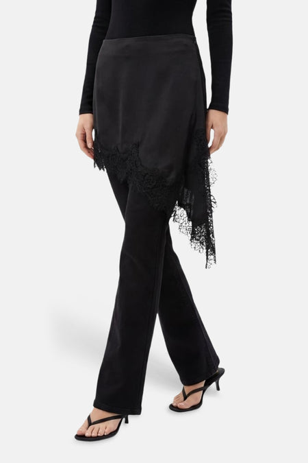 Zwarte korte rok van TALLY WEIJL met asymmetrische kanten rand, gecombineerd met zwarte top, broek en sandalen.