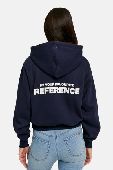 Blauwe sweater met kap van TALLY WEIJL, met witte tekst op de rug, gecombineerd met een jeans.
