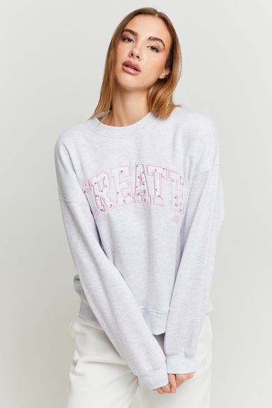 Pull-over gris TALLYALLY WEL avec des lettres sur sur sur, associé à une pantalon blanc.
