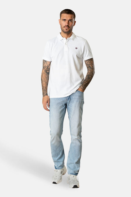 Rechte jeans van lichtblauwe denim van Petrol Industries, gedragen met een wit poloshirt en witte sneakers.