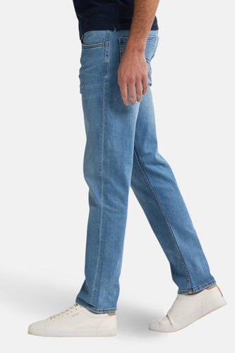 Rechte jeans van lichtblauw denim van Petrol Industries, met witte sneakers en donkerblauw shirt, in zijaanzicht.
