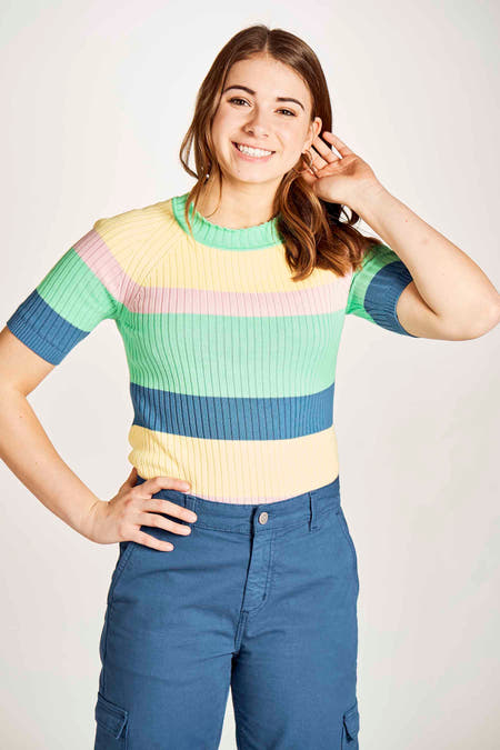 Groene trui van Stien Edlund met pastelkleurige strepen, gecombineerd met blauwe cargo broek.