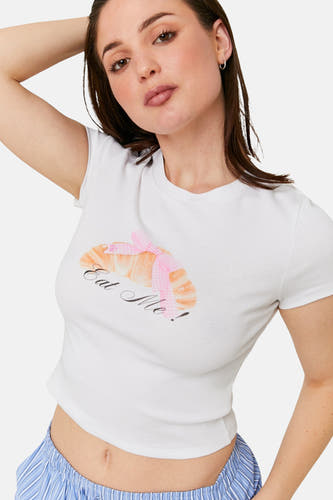 T-shirt blanc à manches courtes de TALLY WEIJL, avec un imprimé croissant et un short bleu et blanc rayé.