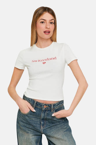 T-shirt blanc à manches courtes de TALLY WEIJL, avec du texte "Suisse" rouge et un cœur, associé à des jeans.