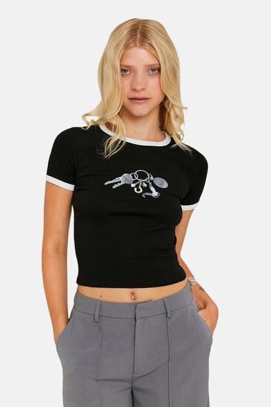 Zwart T-shirt met korte mouwen van TALLY WEIJL, met een print van sleutels, gecombineerd met grijze pantalon.
