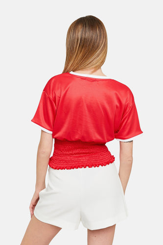 Achterkant van vrouw met rode top en witte shorts.