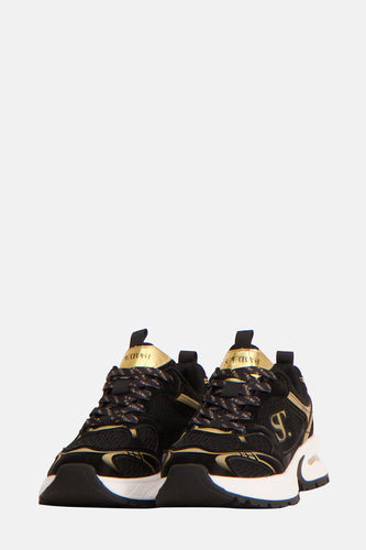 Zwarte en gouden sneakers op een witte achtergrond.
