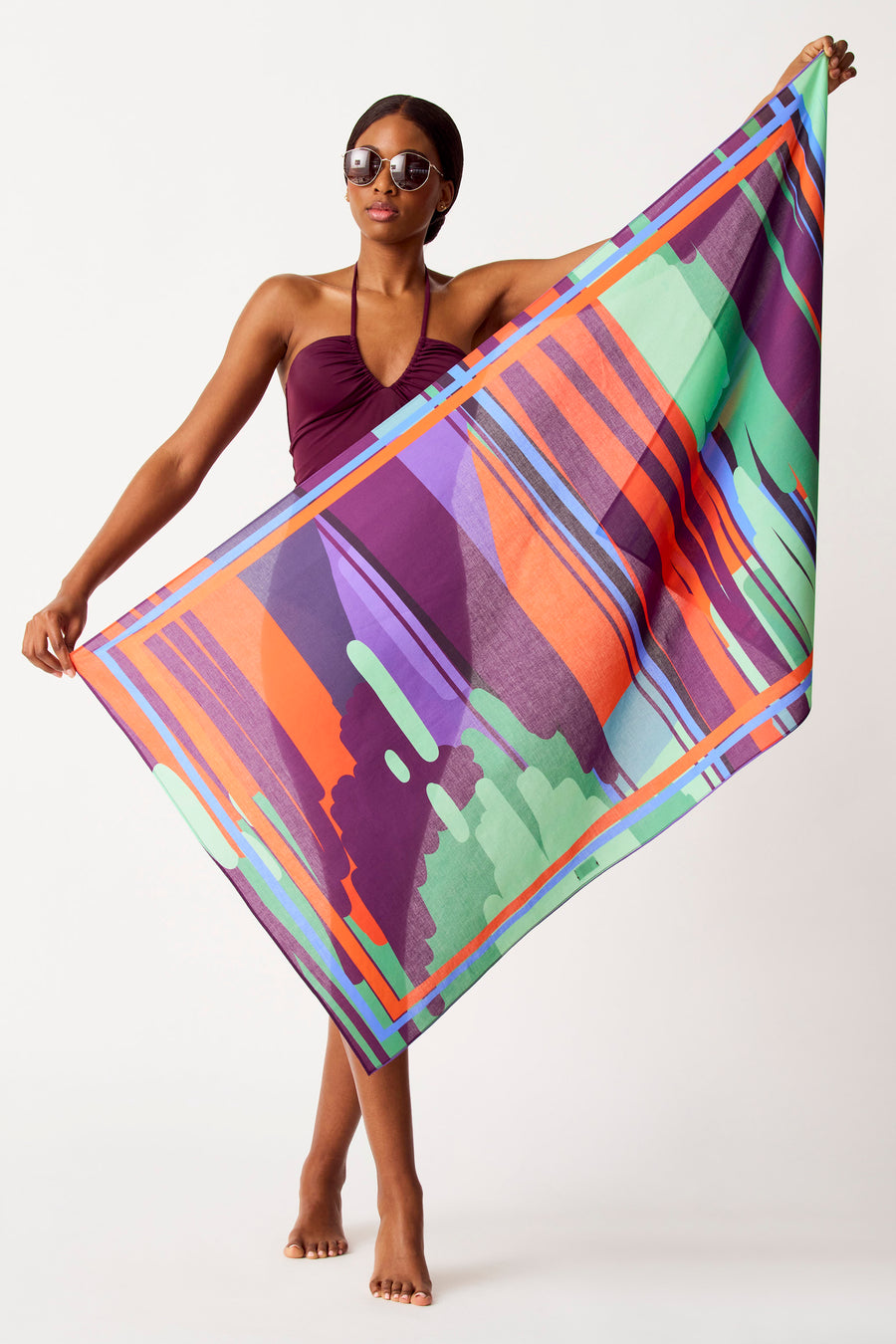 Multikleurige strandkleding van SUNSET STUDIO, met een opvallend geometrisch patroon, gedragen door een model in een donkere badpak.
