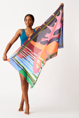 Multicolor strandlaken van SUNSET STUDIO, met een opvallend geometrisch patroon, vastgehouden door een vrouw in een blauw badpak.
