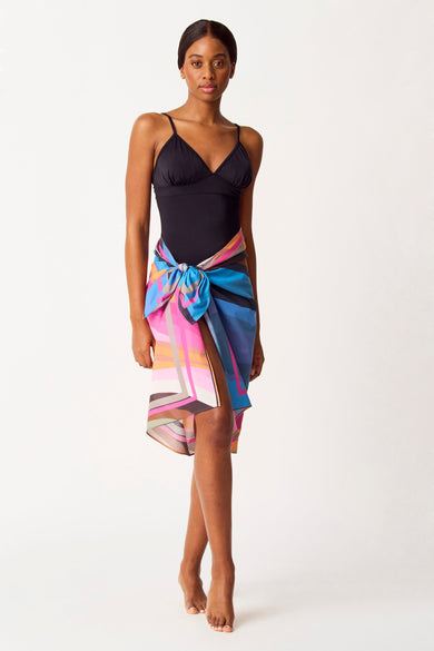 Multicolor beachwear van SUNSET STUDIO, met een geometrisch patroon en gedragen over een zwart badpak.
