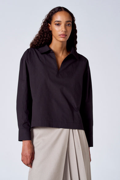 Zwarte blouse met lange mouwen van SUNSET STUDIO, gedragen met een beige rok met plooien.
