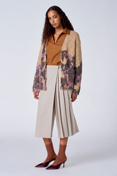 Bruine trui met V-hals van SUNSET STUDIO, met een gebreid vest, beige culottes en bruine glitter sokken met hakken.
