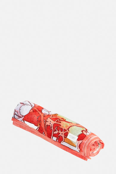 Oranje strandkleding van SUNSET STUDIO, gerold met wit, rode en groene bloemenprint.