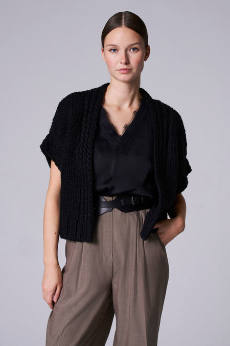 Zwart denim gilet van Astrid Black Label, gedragen over een zwarte top en bruine pantalon.