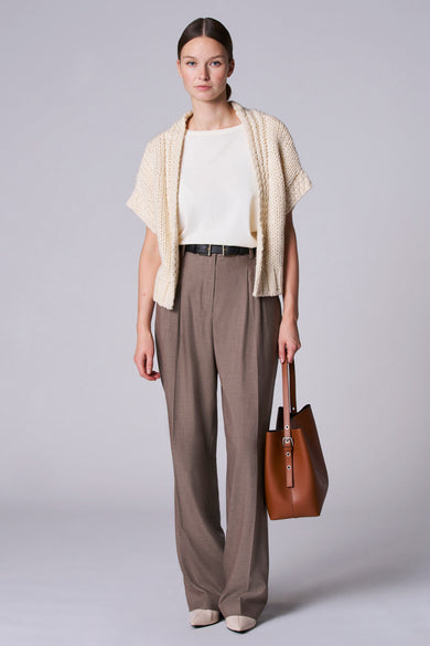Wit gilet van Astrid Black Label, gedragen over een crèmekleurige top met bruine pantalon en een leren tas.
