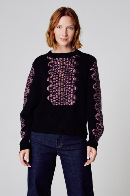 Pull noir avec col rond de Clouds of Fashion, avec un motif graphique en violet et rose.