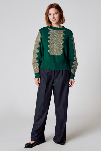 T-shirt vert avec col rond de Clouds of Fashion, doté d'un motif graphique détaillé et de longues manches, associé à un pantalon gris foncé.