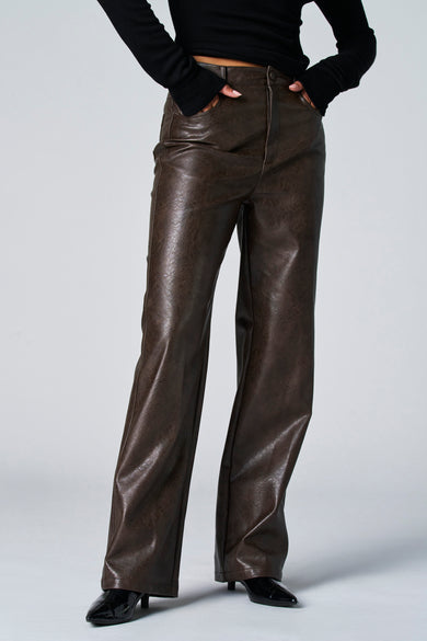 Pantalon brun en cuir imitation d'Astrid Black Label, avec poches et associé à une chemise noire et des escarpins noirs.