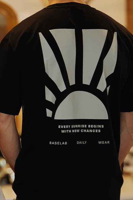 Zwart T-shirt met korte mouwen van BASELAB, met grafische print van een opkomende zon op de achterkant.
