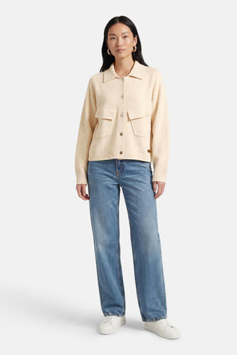 Ecru gilet van ADORE, met lange mouwen, knoopsluiting en opgestikte zakken, gecombineerd met een blauwe jeans en witte sneakers.
