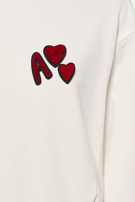 Sweat-shirt blanc ADORE avec lettre "A" rouge et applications en forme de cœur.