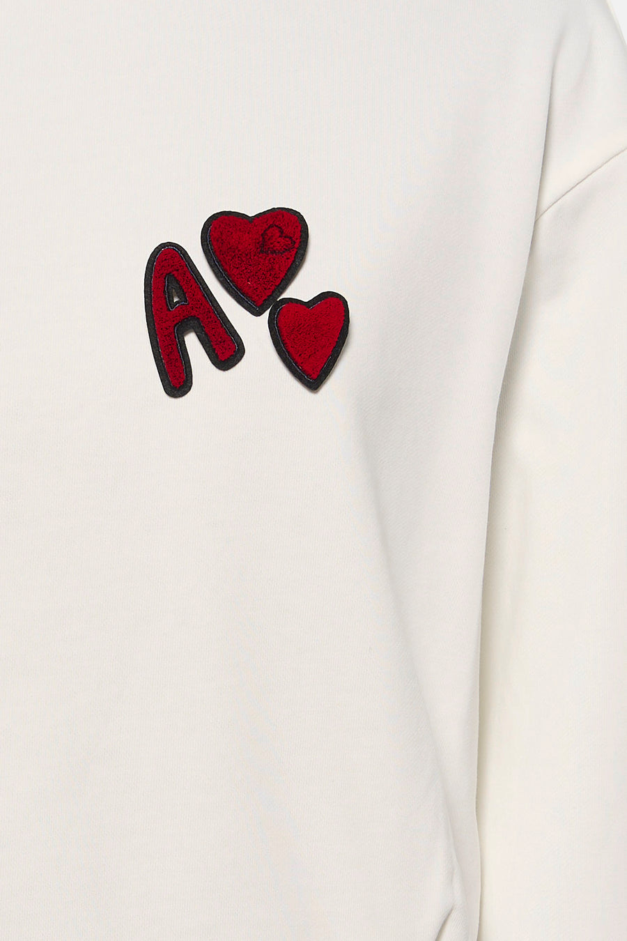 Witte sweater van ADORE met rode letter "A" en hartjes applicaties.
