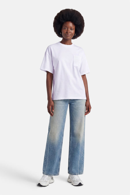Witte korte mouwen t-shirt met borstzakje van ADORE, gedragen met wijde jeans en witte sneakers, front view