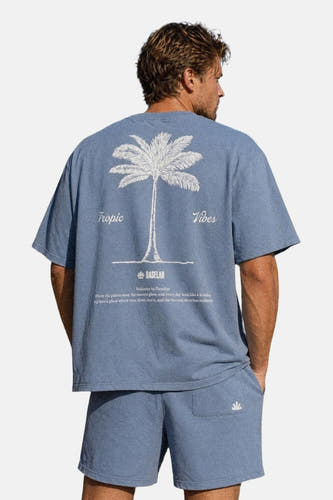 Blauwe korte mouwen t-shirt van BASELAB, achterkant met witte palmboomprint en tekst, model in lifestyle pose
