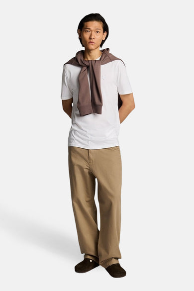 Wit T-shirt met korte mouwen van LYLE & SCOTT gedragen door staande man met bruine trui over de schouders en beige broek.