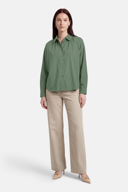 Groen hemd van ADORE, met lange mouwen, gedragen met een beige broek en pumps.
