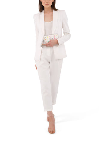 Veelkleurige portefeuille van Guess met patroon en handriem, gecombineerd met een witte damesbroek en een blazer.

