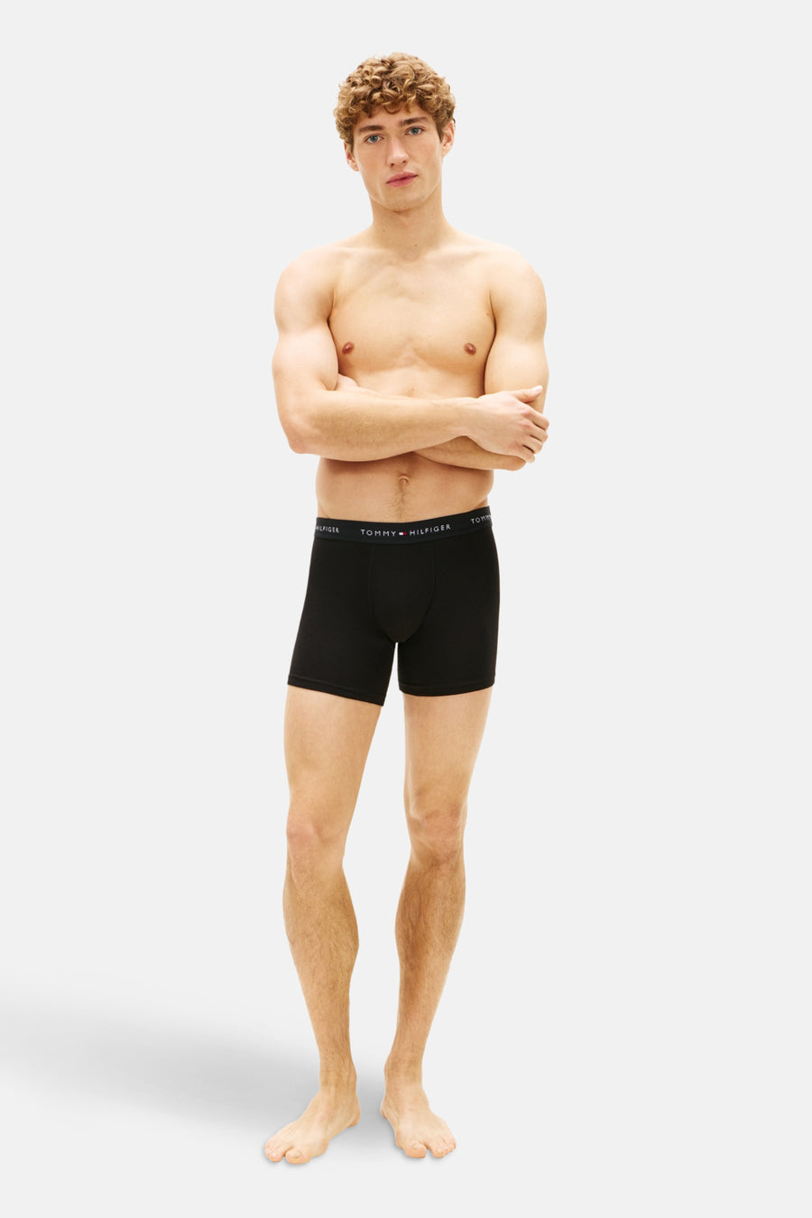 Zwarte boxers van Tommy Jeans, gedragen door een model met gekruiste armen.
