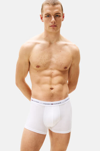 Boîtes de boxers blancs de TOMMY JEANS, portées par un homme avec les mains sur le dos.