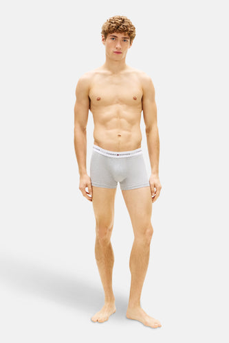 Grijze boxershort van Tommy Hilfiger, gedragen door een man met een gespierd bovenlijf, op een witte achtergrond.
