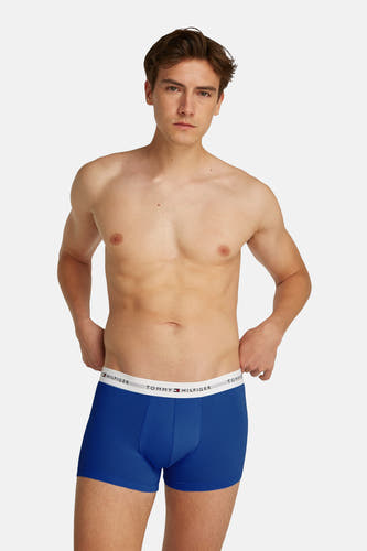 Blauwe boxershort van TOMMY JEANS, gedragen door een man, met witte logoband aan de bovenkant.