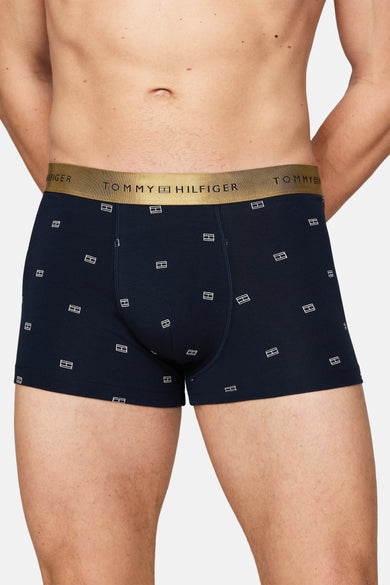 Blauwe boxershort van TOMMY JEANS met wit logo patroon en gouden tailleband.
