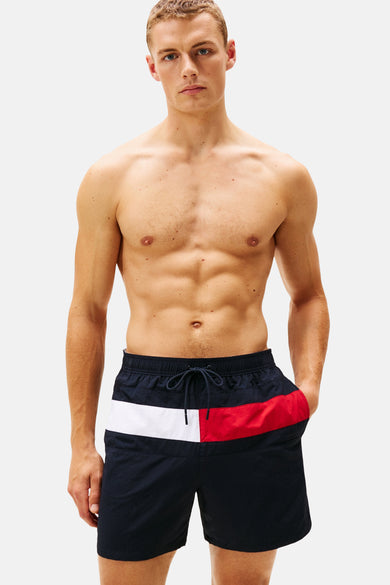 Blauwe zwemshort van Tommy Jeans, met een witte en rode baan en een trekkoord.
